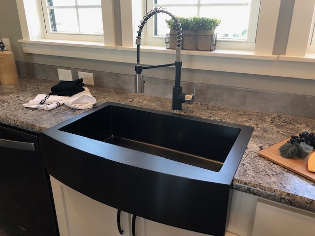 black farm house sink in a small kitchen